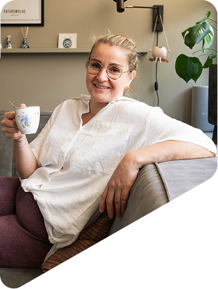 Portret van Wendy Wielenga, ontspannen op de bank met een kop koffie en een uitnodigende glimlach